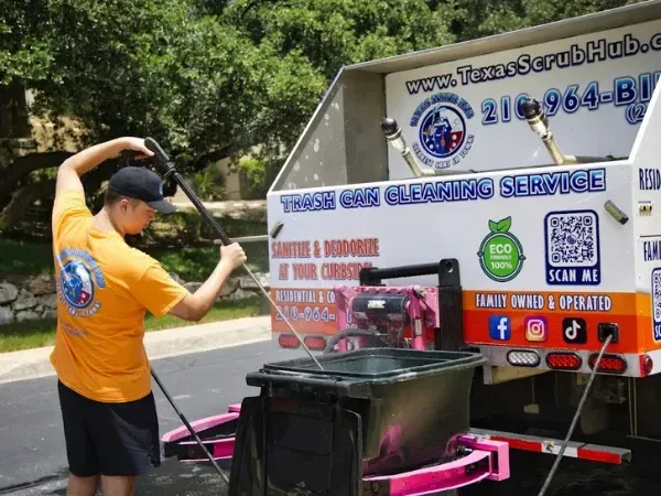 Technician using cleaning equipment to sanitize trash bin