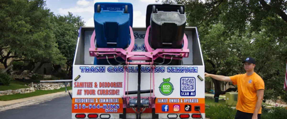 Trash bin cleaning truck lifting two bins for sanitizing, with a technician standing beside the equipment.