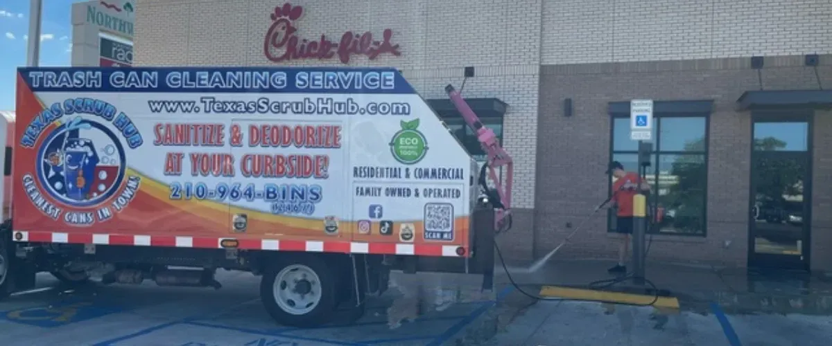 Trash can cleaning service truck parked at Chick-fil-A while a worker pressure washes the sidewalk