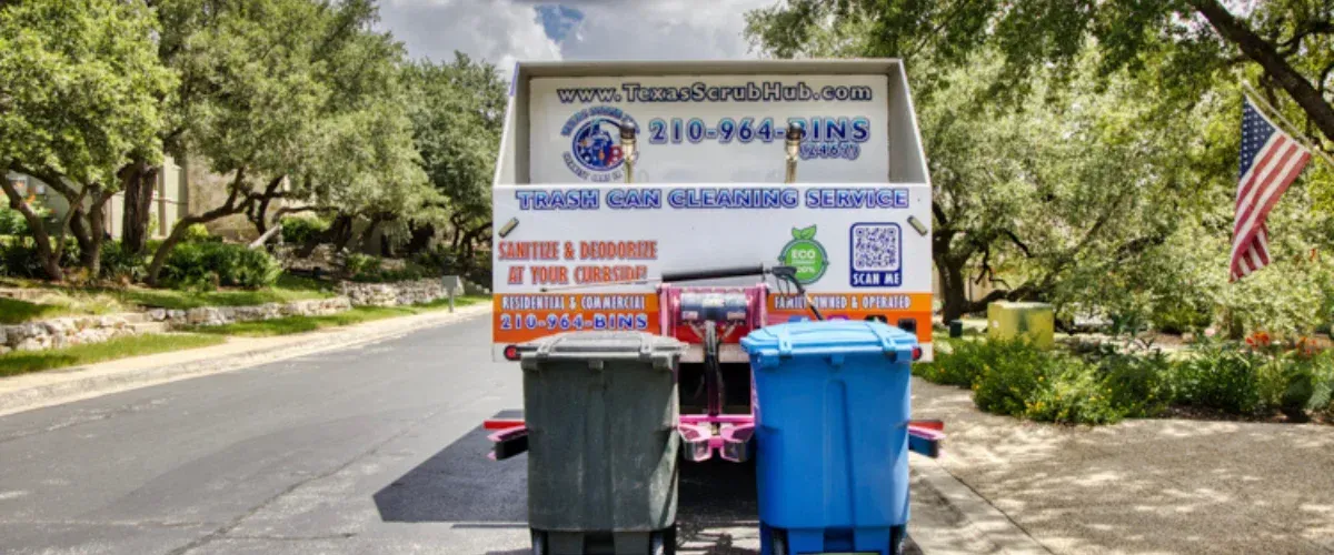 Rear view of a white trash can cleaning service truck with 'Texas ScrubHub' branding, cleaning two trash cans on a suburban street.