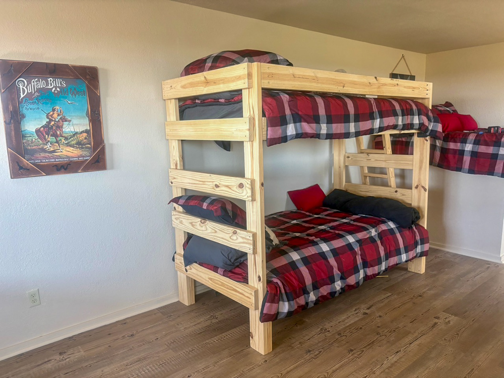 Interior of the barn’s upstairs living area at Rock n Wood Farm & Ranch featuring wooden bunk beds with plaid bedding and rustic Western décor.