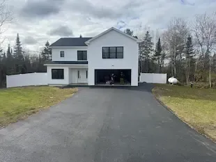 A newly sealcoated driveway in front of a white house in Newport, Maine
