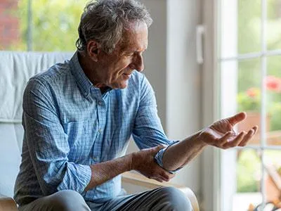 Man holding his elbow in pain, indicating the need for naturopathic regenerative treatments for upper extremity conditions like rotator cuff injuries and carpal tunnel syndrome.