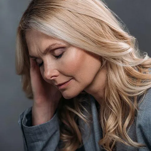 Woman holding her head in pain, highlighting the importance of natural treatments for migraines and tension headaches.