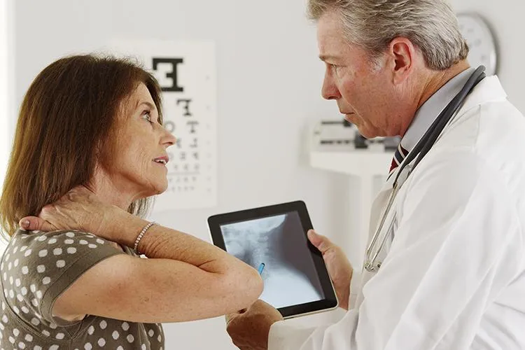 Doctor showing an X-ray to a patient with neck pain, discussing personalized treatment options at Naturopathic Physicians Group in Scottsdale.