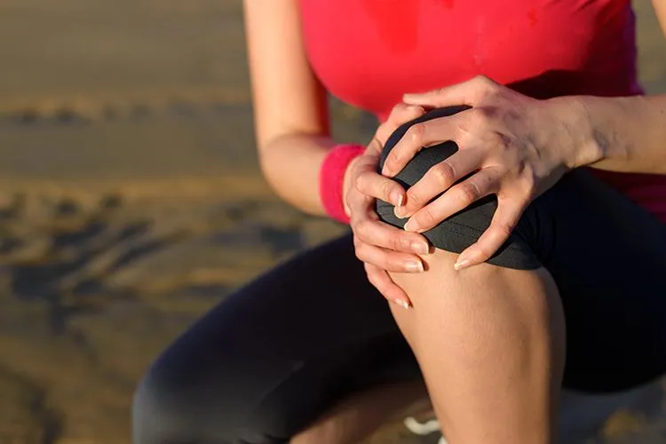 Woman holding her knee in pain, symbolizing natural treatments for knee pain relief at Naturopathic Physicians Group.