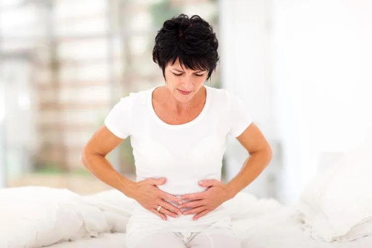 Woman holding her stomach in discomfort, depicting the need for holistic treatments for digestive health concerns.