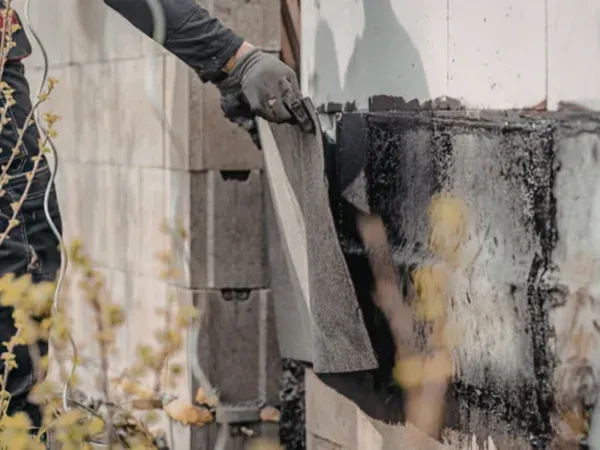 A dilapidated, cluttered room featuring a messy desk, an open wardrobe, discarded furniture, and debris on the floor near a window.