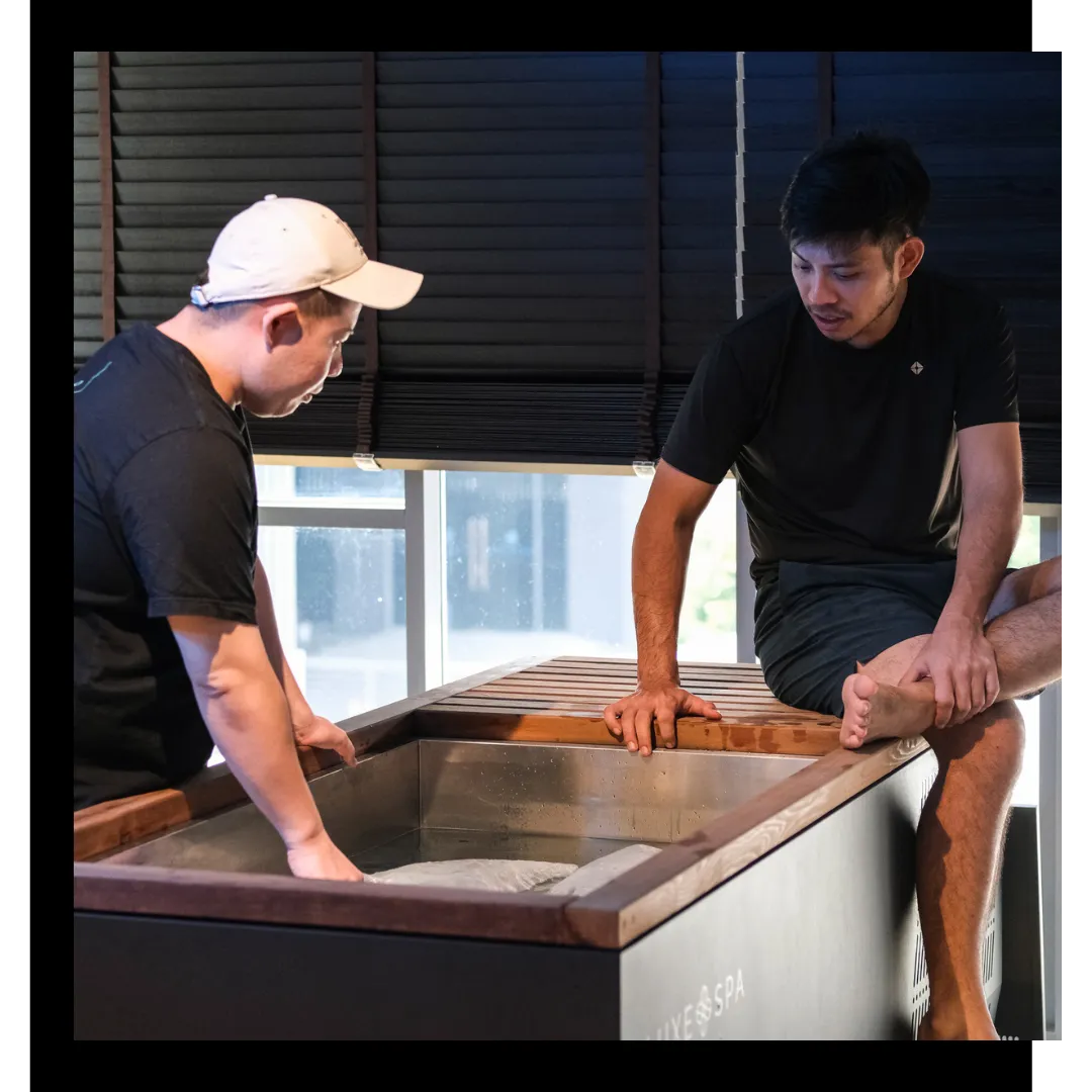 Two men testing a cold plunge temperature