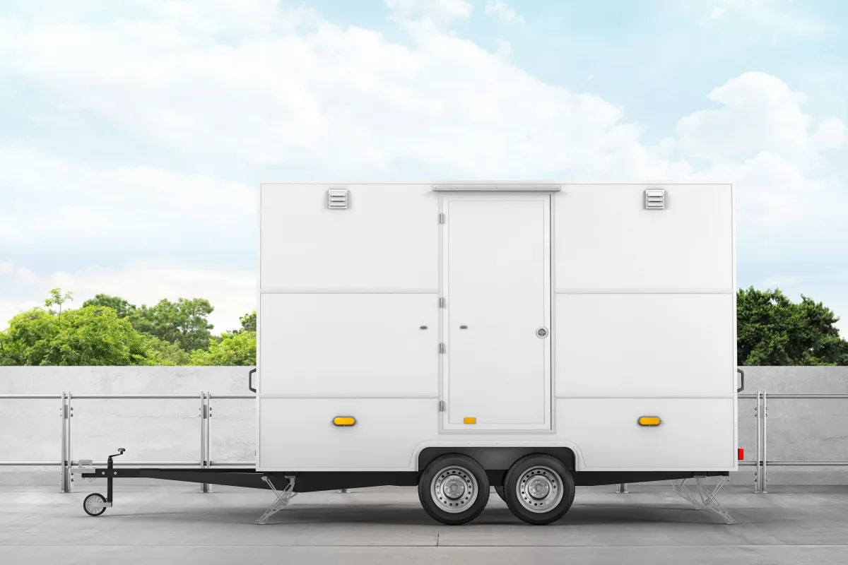 small white trailer with single door used for luxury porta potty parked on cement road