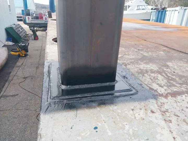 Welded steel column baseplate on industrial dock, demonstrating heavy-duty on-site MIG welding service by Warrior Welding