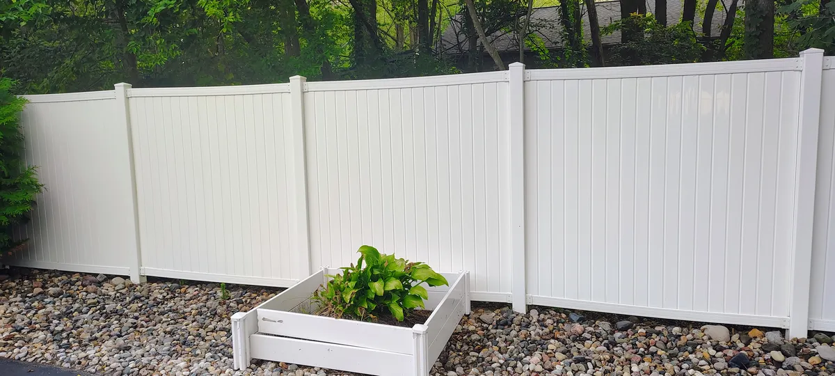 A close-up of a clean wooden fence featuring the blue JC Hydro Blast company logo.