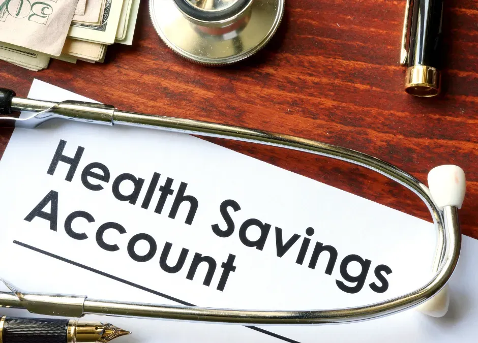 Document labeled “Health Savings Account” with stethoscope, cash, and pen on desk.
