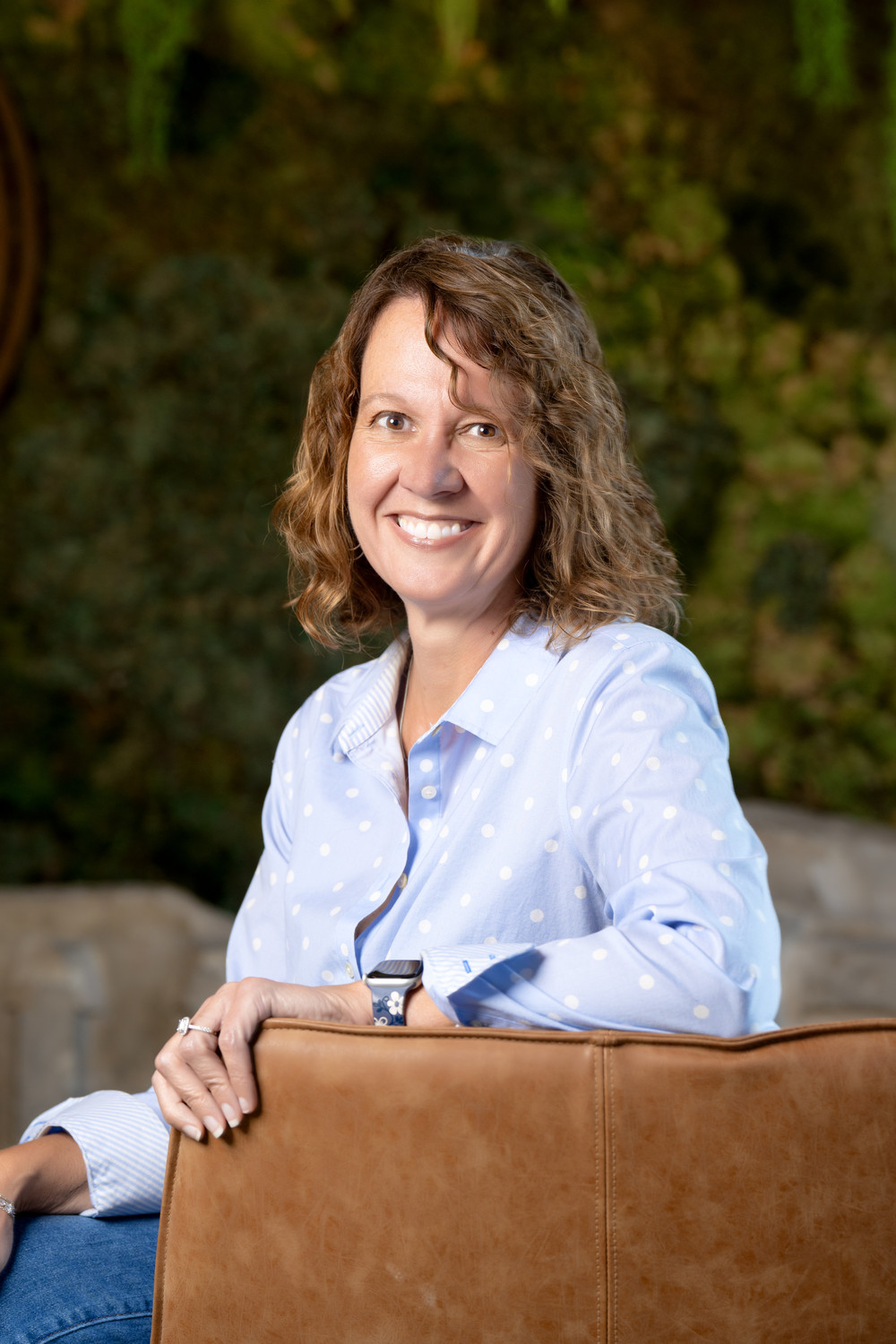Laura on a brown leather chair smiling into the camera