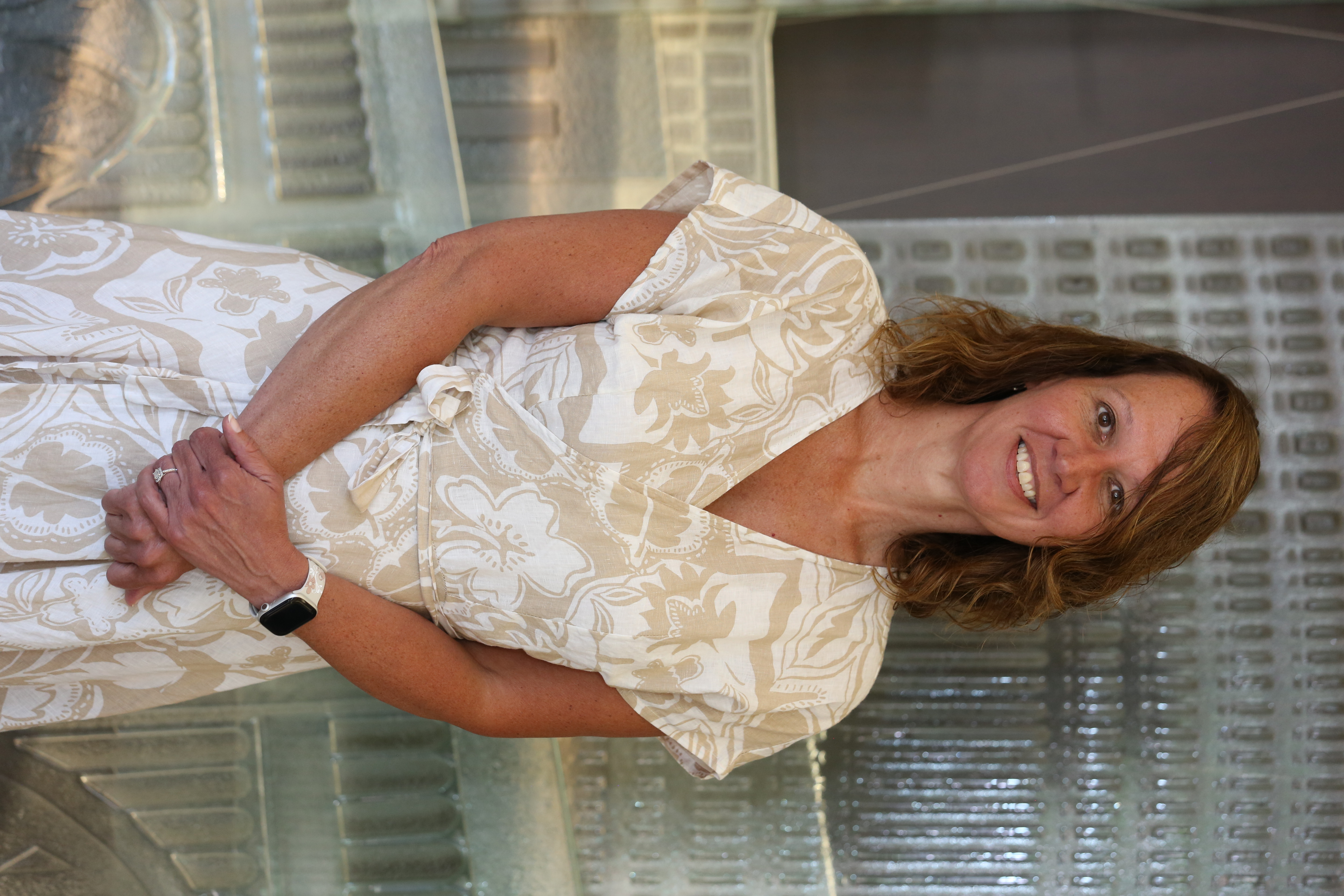Laura in a white and tan print wrap dress, smiling at the camera.