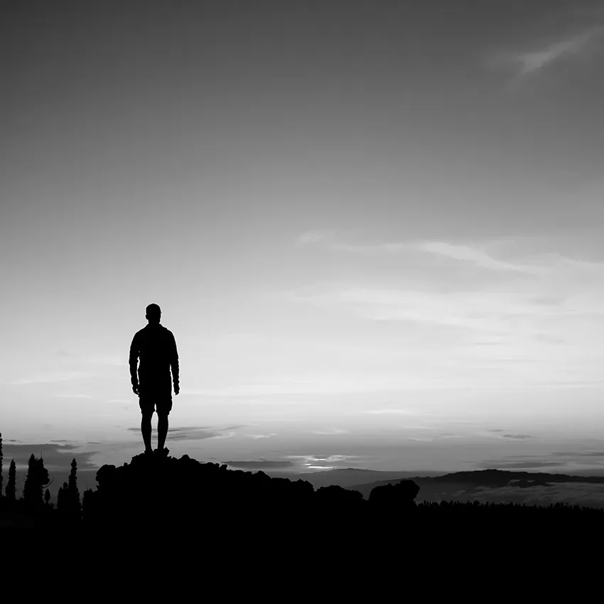 A solitary figure standing before a wide, quiet horizon