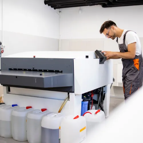 print worker operating computer to plate machine in print shop