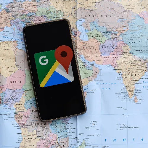 mobile phone with google maps logo and world map in background