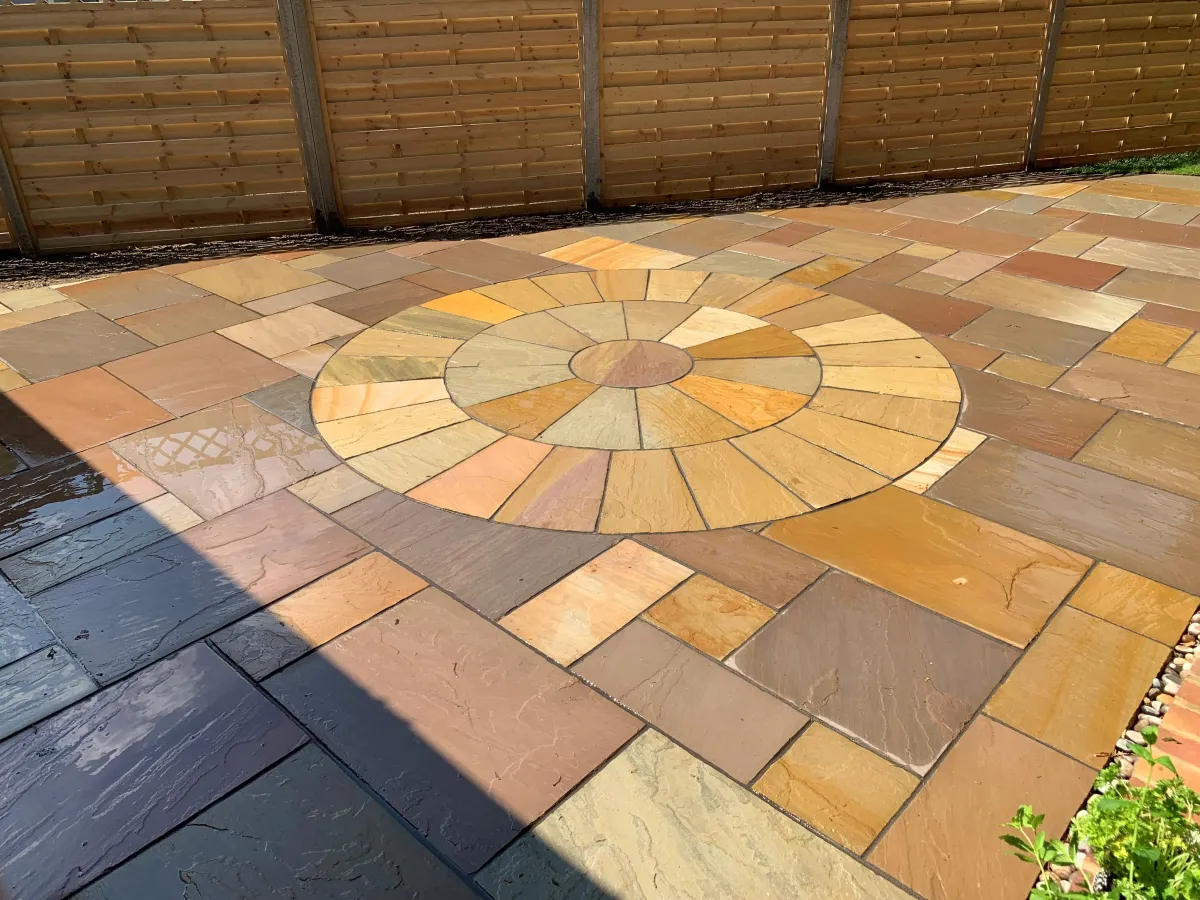 A natural sandstone patio with a circular pattern in the middle.