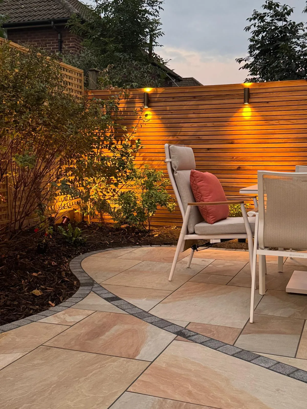 The patio is crafted from high-quality materials, creating a durable and stylish outdoor living space. Comfortable patio furniture is arranged on the smooth surface, inviting relaxation and social gatherings. Lush plants and vibrant flowers adorn the patio's edges, adding a touch of natural beauty and tranquility to the overall ambiance.