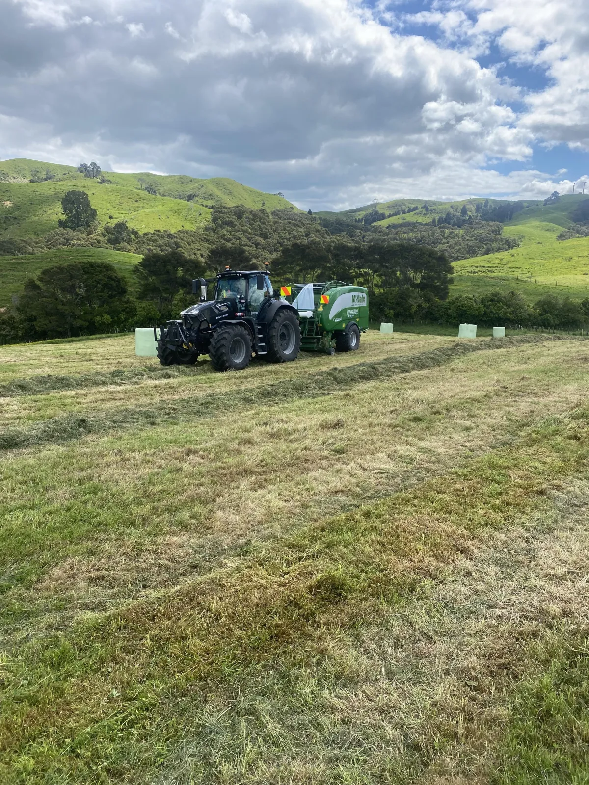  Tractor working on round bale grass silage in Waikato paddock for Illawarra Contracting