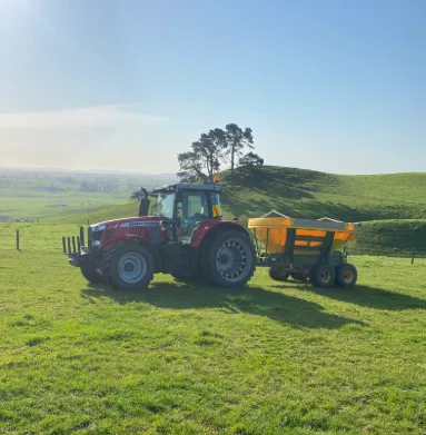  Tractor towing orange seeder for undersowing and regrassing on Waikato farm