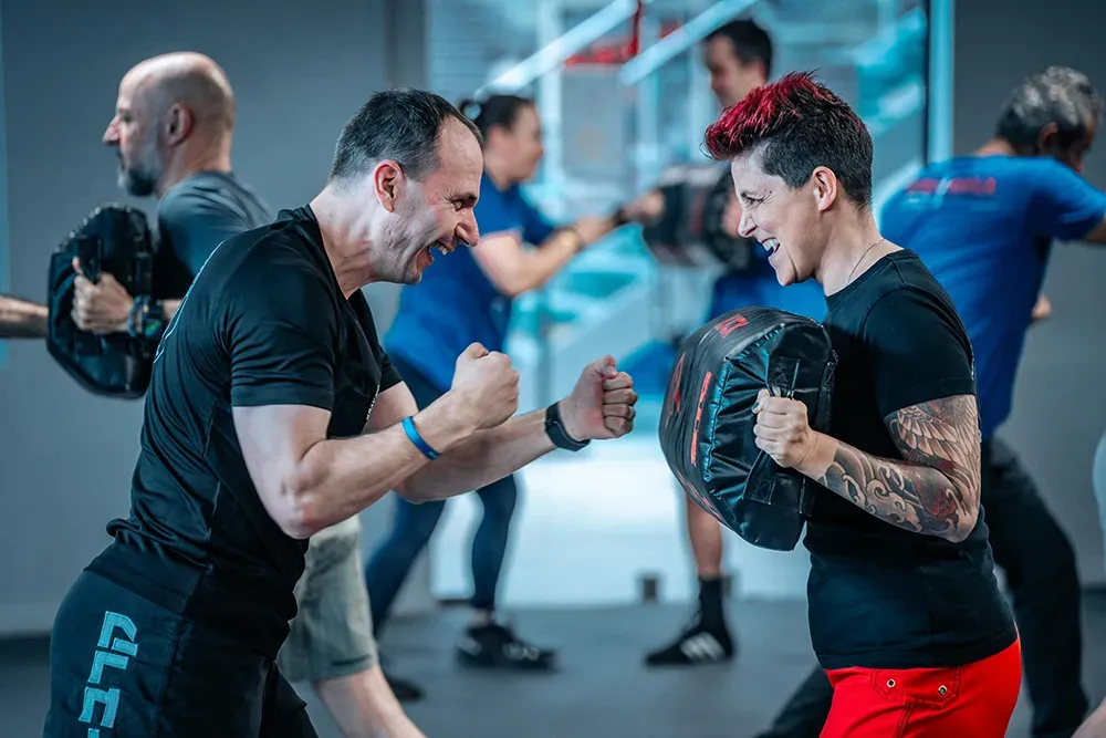 A participant practising on pads with a Krav Maga coach