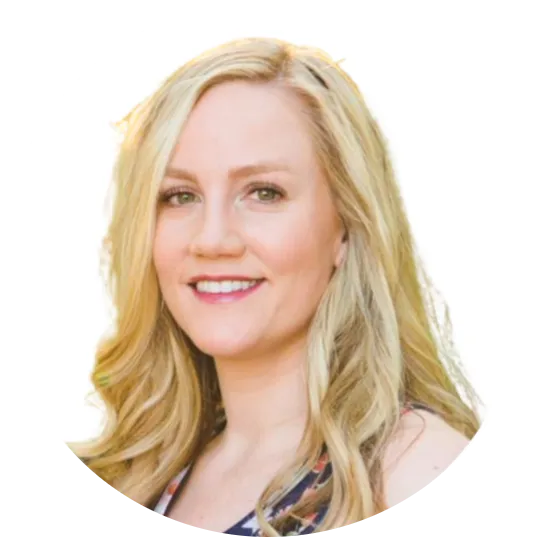 A woman with blonde hair smiles, showcasing her layered hairstyle and wearing stylish clothing.