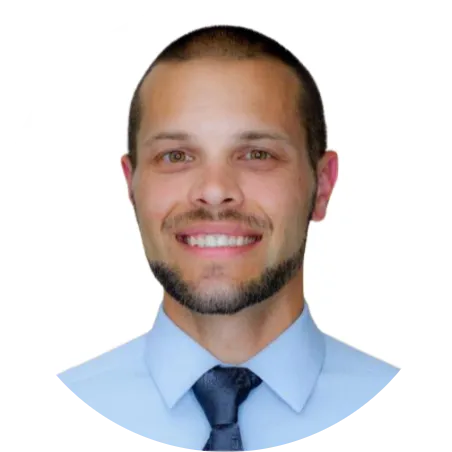 A man in a blue shirt and tie smiles, showcasing his facial features in a headshot.
