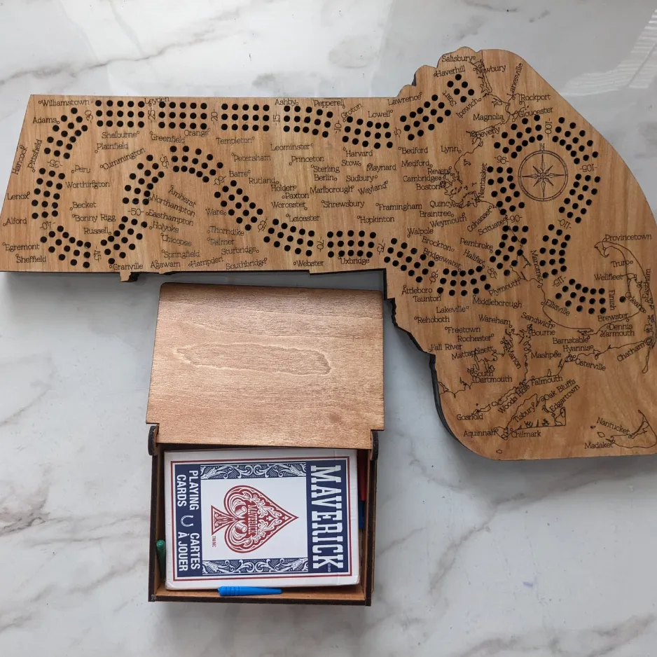 Custom laser-engraved wooden cribbage board cut into the shape of the state of Massachusetts, paired with a matching wooden playing card storage box