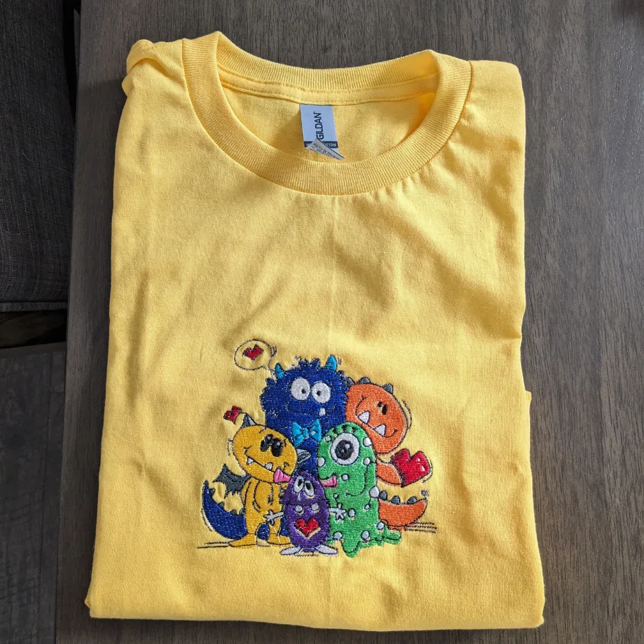 Yellow T-shirt with colorful embroidered characters.