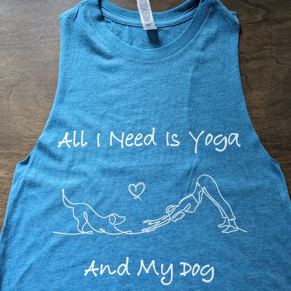 Blue sleeveless tank top featuring a white graphic reading All I Need Is Yoga And My Dog