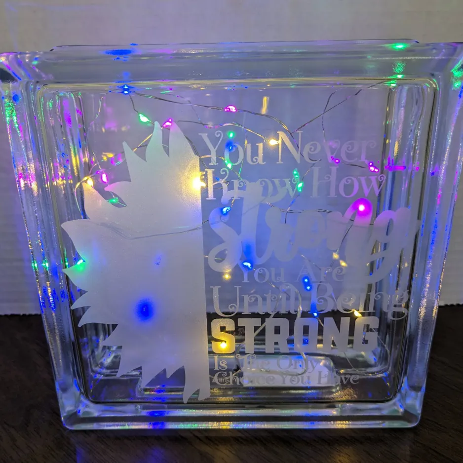 Decorative glass block filled with multi-colored fairy lights and an inspirational quote