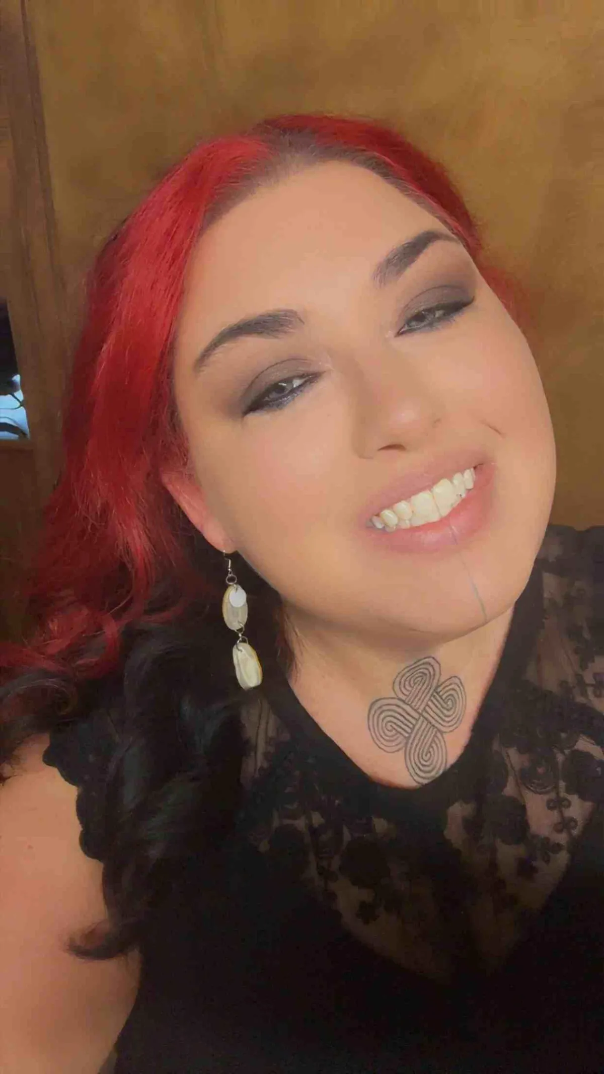 Jill Medina, local poet smiling for the camera. Photo depicts a woman of native american decent with red hair in a black t-shirt and earrings.