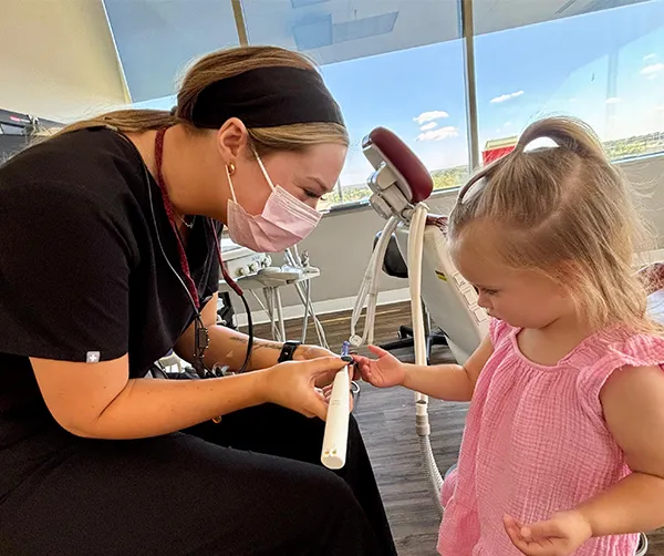 Dental assistant with mask o interacting with a child