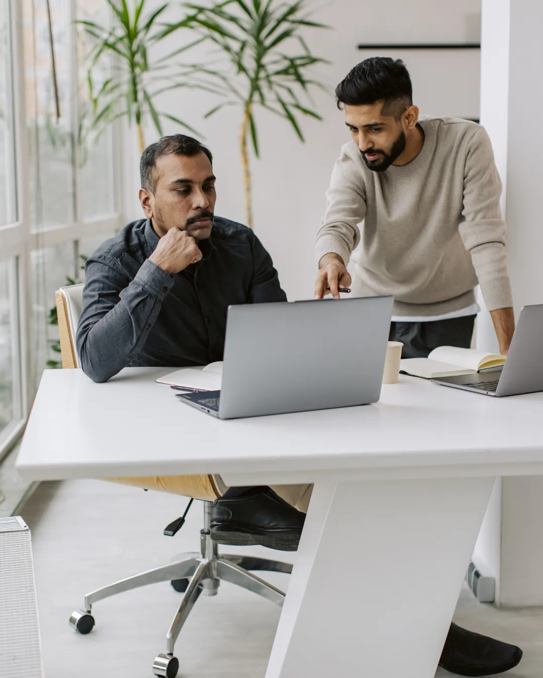 Two billing professionals collaborating on insurance claims at modern office workspace