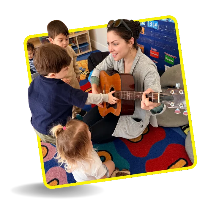 Preschool teacher playing guitar with young children during a music activity at Beginnings Learning Center in Santa Monica