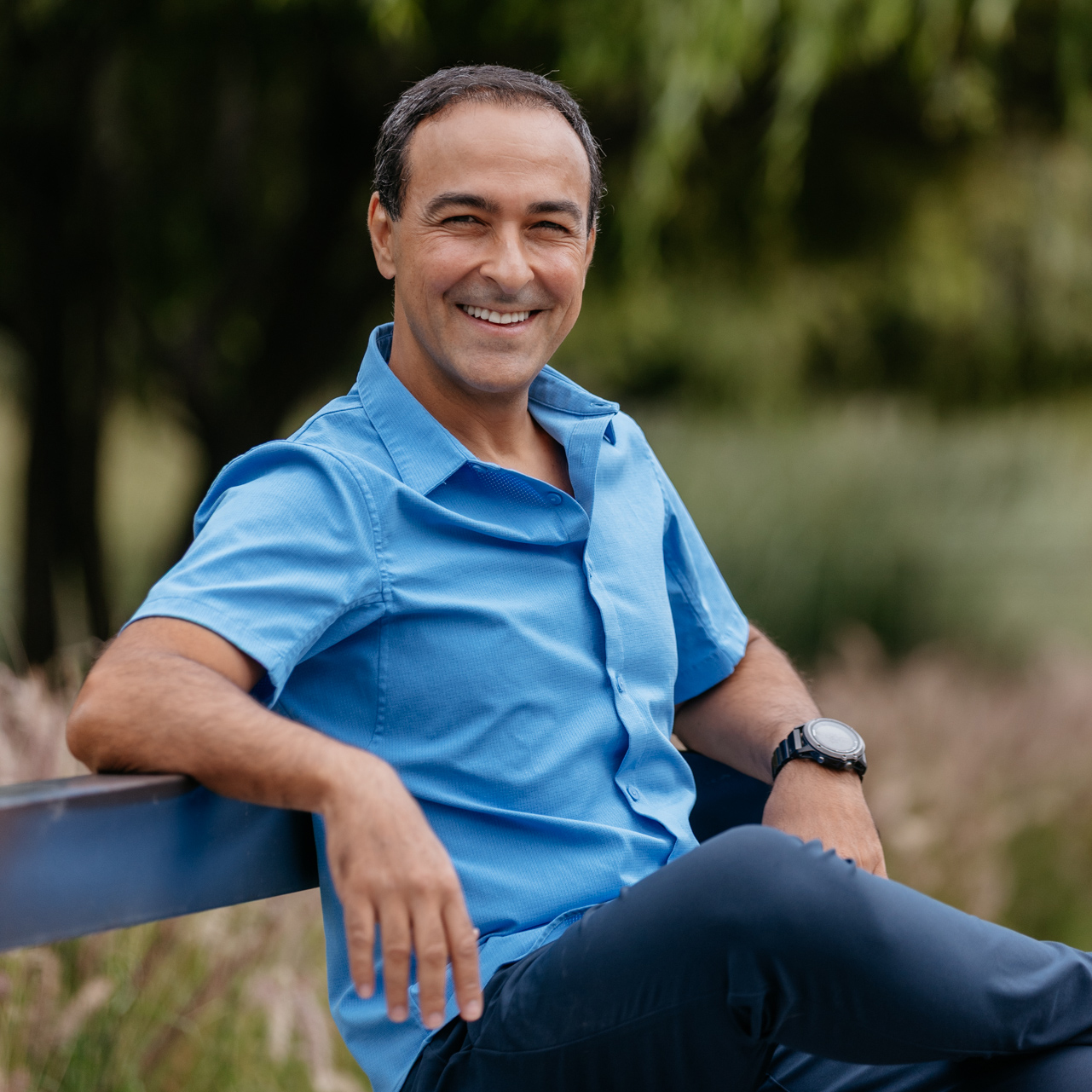 A diverse group of adults, each holding a digital device, gather around a modern registration kiosk in a bright, open event space. The group appears excited and engaged, with natural light streaming through large windows. The scene conveys inclusivity, efficiency, and a welcoming atmosphere, emphasizing a smooth registration experience.