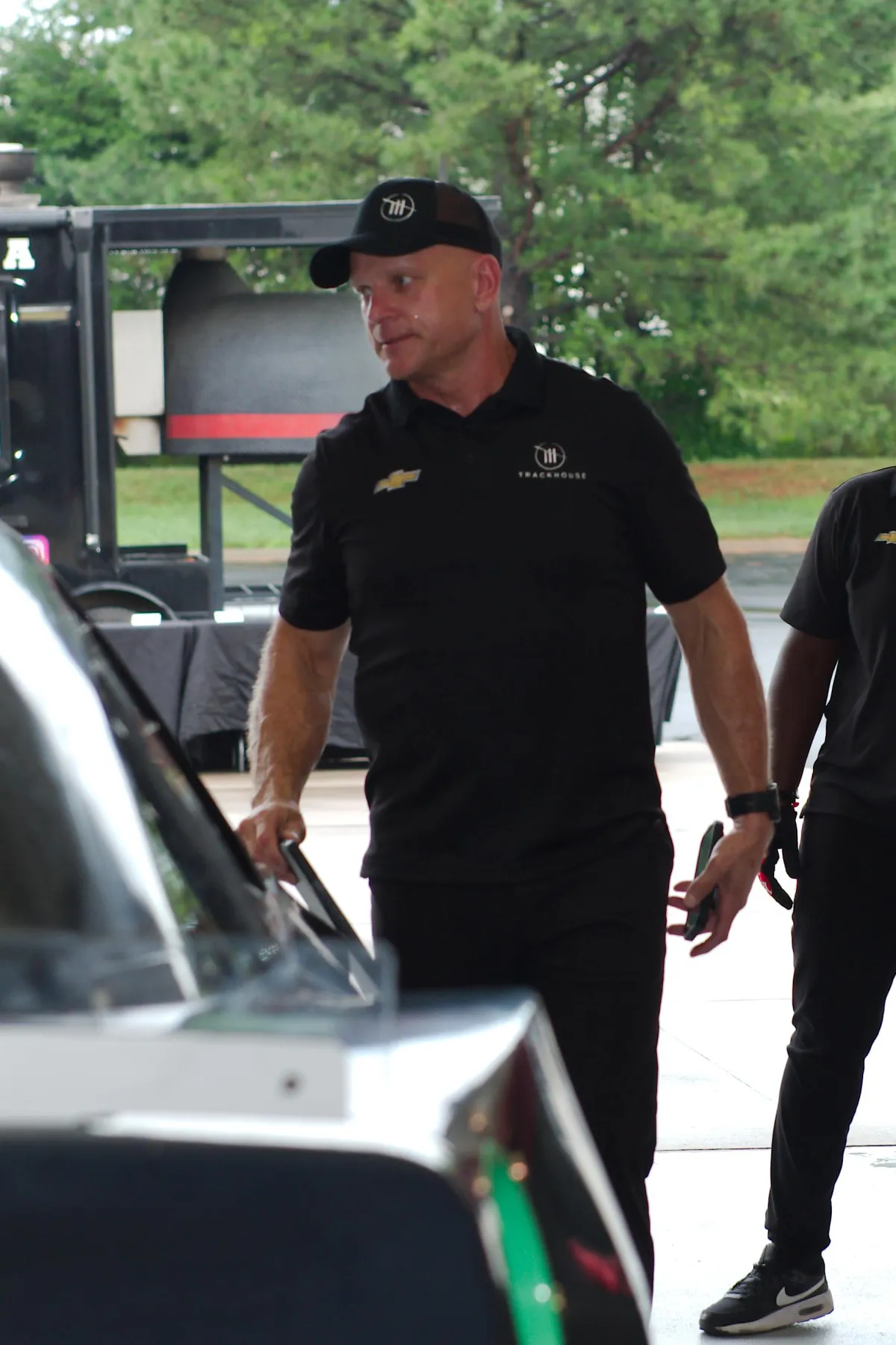 Shaun Peet standing beside a race car during a pit crew session.”