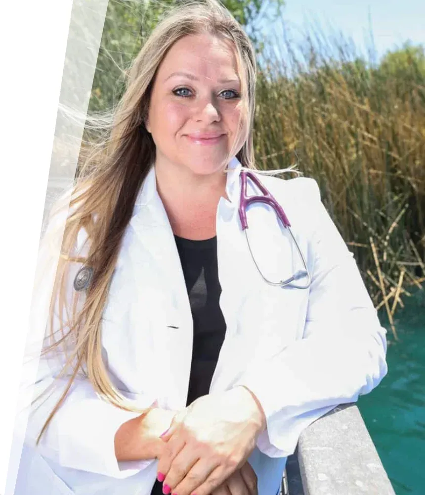 Nurse Nikki, founder of Holistic Healing Heroes, standing outdoors in a white coat with stethoscope, smiling confidently 