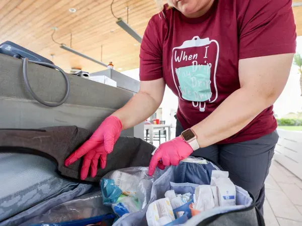 Nurse wearing gloves organizing IV therapy supplies from medical kit during mobile hydration service