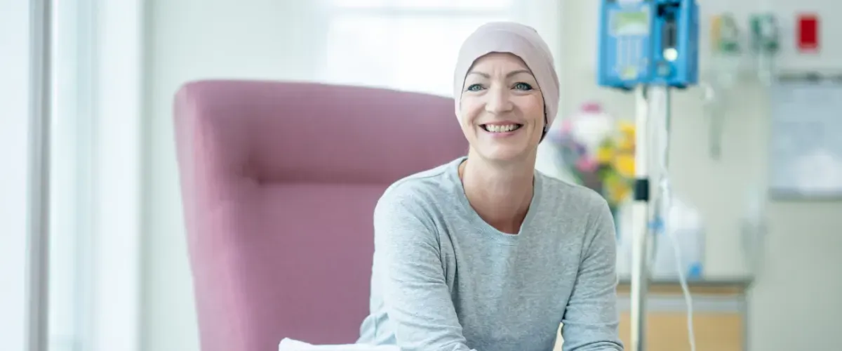 Smiling cancer patient receiving treatment in a hospital infusion chair.