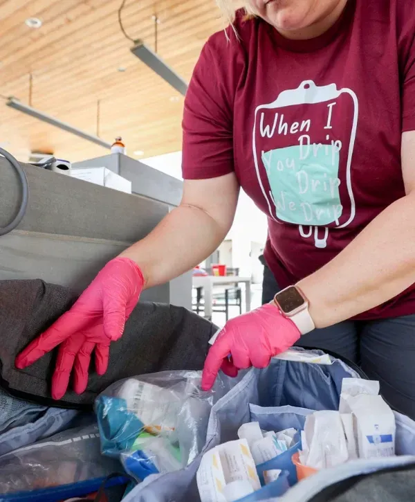Mobile IV therapy nurse organizing medical supplies in a travel bag.