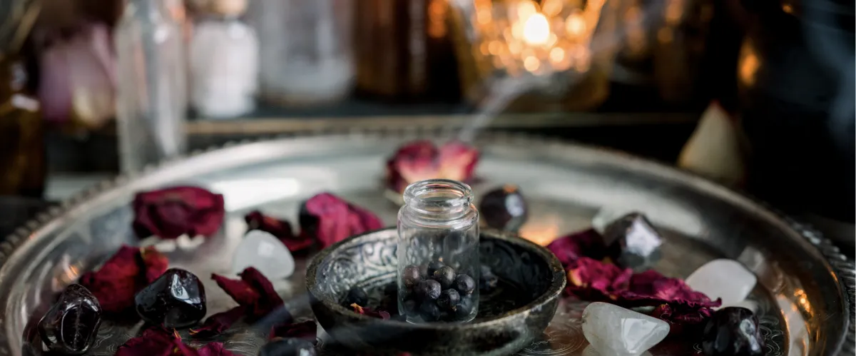 Sacred altar with crystal vial, rose petals, clear quartz, and black obsidian stones on silver tray, symbolizing energy purification and spiritual alignment practices for soul-led entrepreneurs.