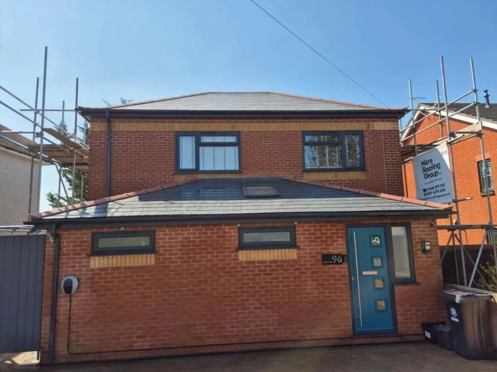 Rooftops with dormers sit under a cloudy sky.