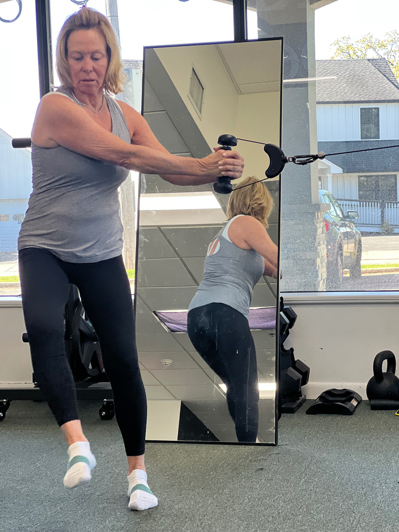 Women’s personal trainer in a personal training studio near Saddle River, NJ demonstrating a cable exercise for functional fitness and strength training.