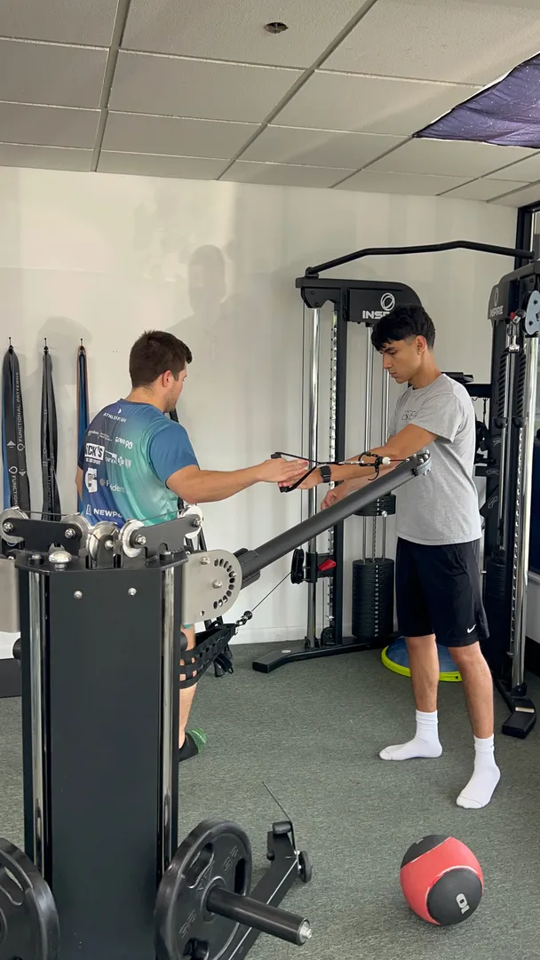 Suspension training equipment in a personal training studio with a client working out in the background.