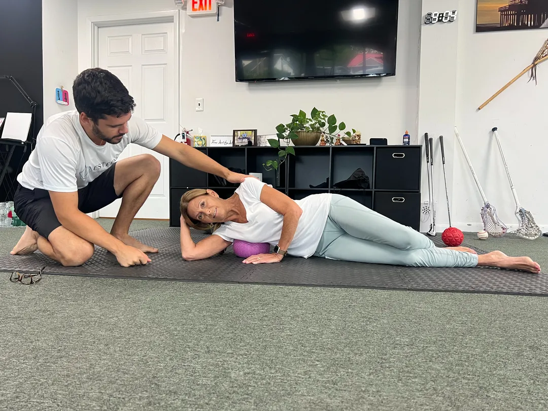 Personal trainer guiding a woman through a side-lying mobility exercise during a one-on-one training session near Ramsey, NJ.