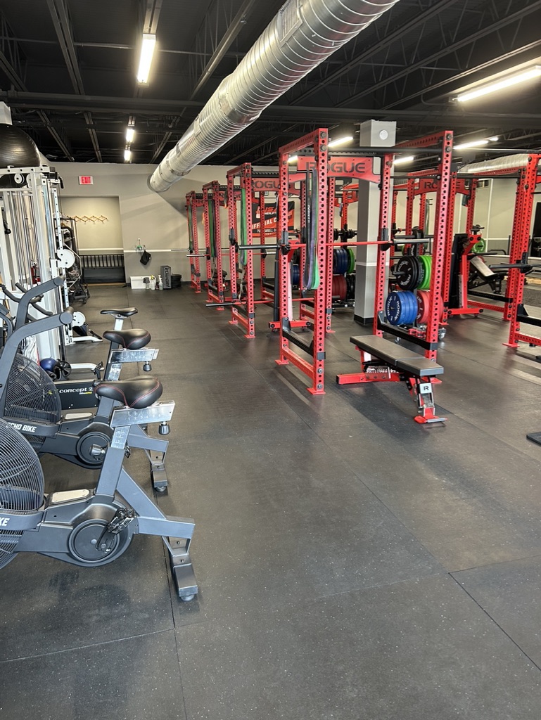 Physical Therapy clinic with modern gym equipment. Including barbells, power racks, benches, bikes and free weights. 