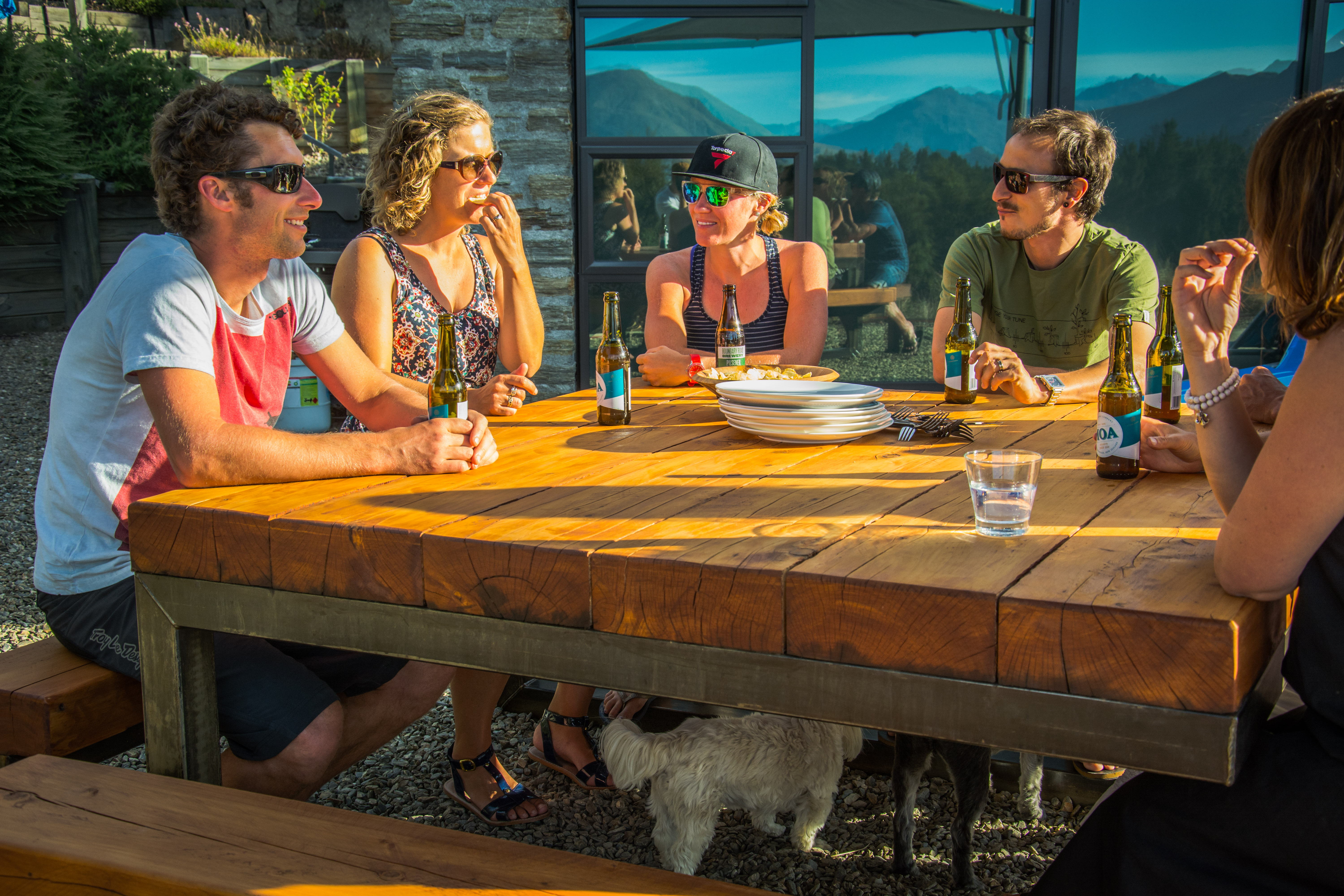 Long festive lunch gathering with more than ten friends seated around a rustic wooden table
